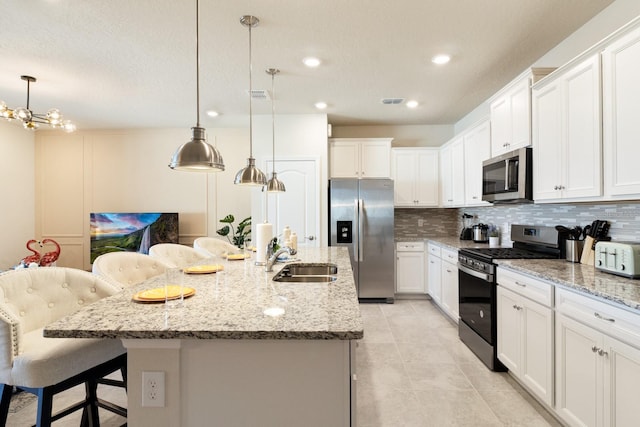 kitchen featuring tasteful backsplash, sink, a breakfast bar, appliances with stainless steel finishes, and a kitchen island with sink