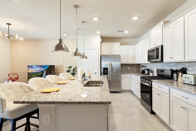 7143 Oakmoss Loop, Davenport, FL 33837 - kitchen featuring appliances with stainless steel finishes, a sink, backsplash, a kitchen bar, and white cabinetry