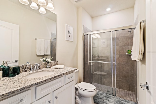 bathroom with a shower with door, vanity, and toilet