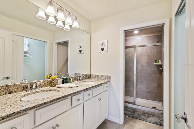 bathroom featuring dual vanity, a shower with door, tile patterned flooring, and a textured ceiling