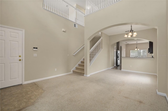 carpeted entryway with an inviting chandelier and a high ceiling