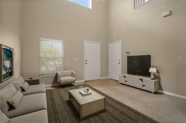 carpeted living room with a healthy amount of sunlight and a towering ceiling