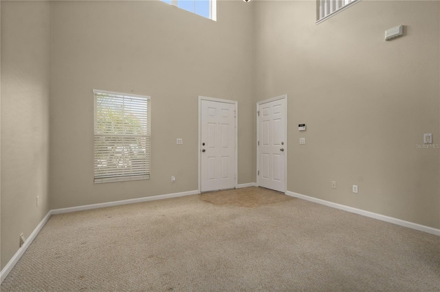 unfurnished room with a high ceiling and light colored carpet