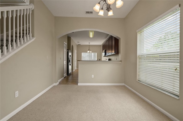 empty room featuring carpet floors and a chandelier