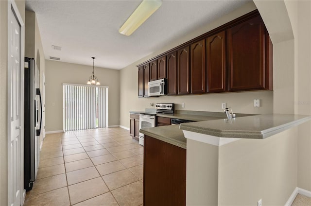 kitchen featuring pendant lighting, light tile patterned floors, dark brown cabinets, stainless steel appliances, and kitchen peninsula