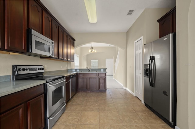 kitchen with pendant lighting, sink, light tile patterned floors, appliances with stainless steel finishes, and kitchen peninsula