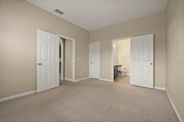 unfurnished bedroom featuring connected bathroom and light carpet