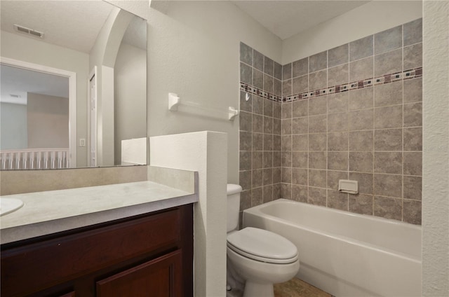 full bathroom featuring vanity, tiled shower / bath combo, and toilet