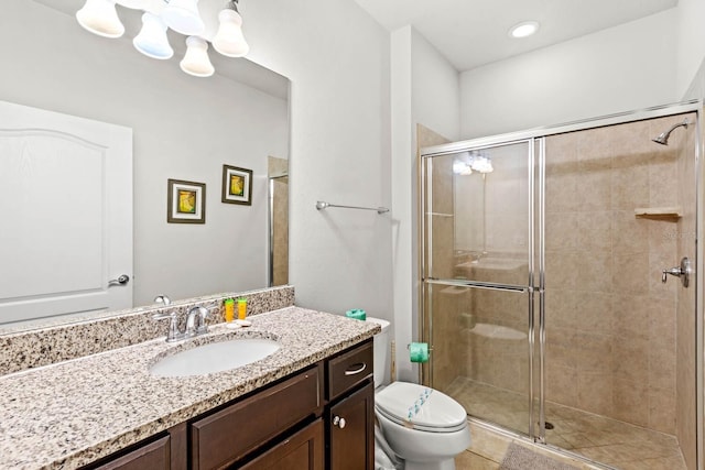 bathroom featuring tile patterned flooring, vanity, a shower with shower door, toilet, and a chandelier