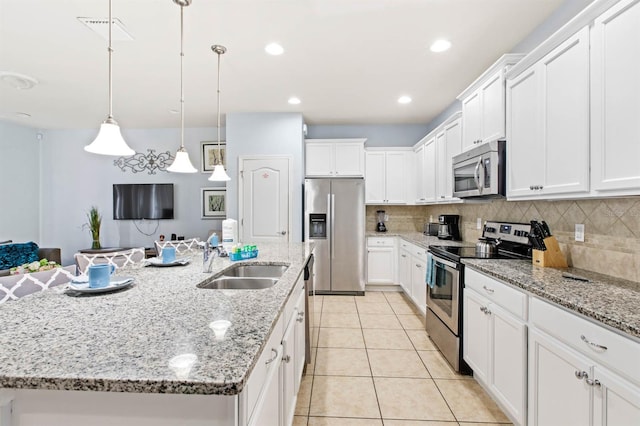 kitchen with sink, an island with sink, pendant lighting, stainless steel appliances, and white cabinets