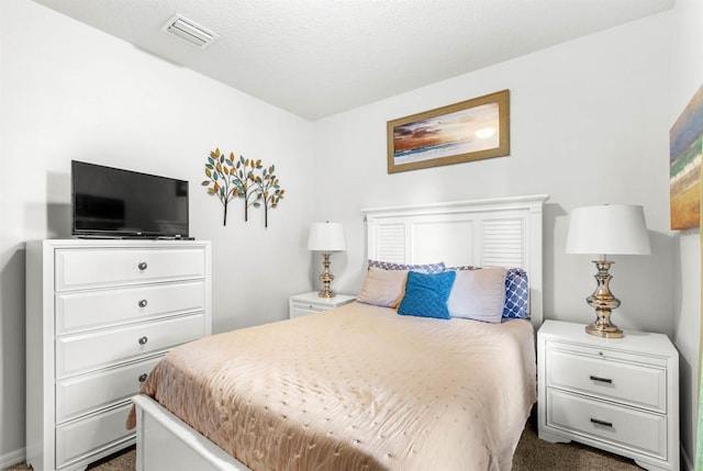 bedroom with a textured ceiling and dark colored carpet