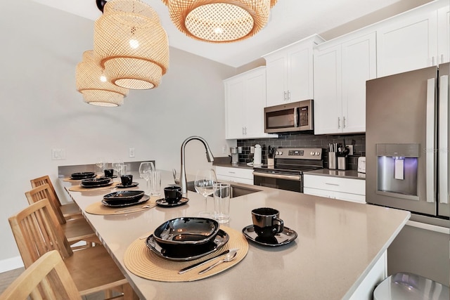 kitchen with a breakfast bar area, stainless steel appliances, white cabinets, sink, and decorative backsplash