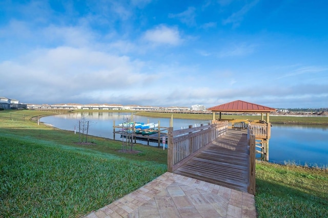 view of dock with a water view, a lawn, and a gazebo