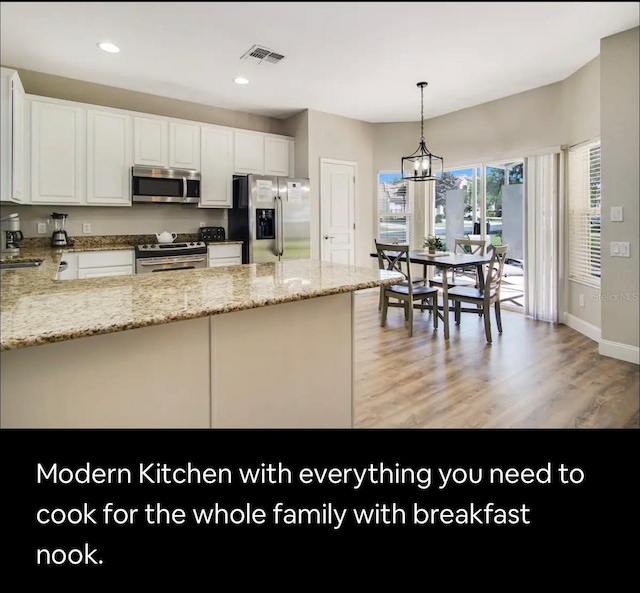 kitchen featuring white cabinets, appliances with stainless steel finishes, decorative light fixtures, light hardwood / wood-style floors, and light stone counters