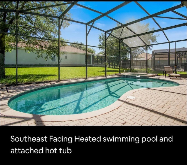 view of pool with a lanai, a yard, an in ground hot tub, and a patio