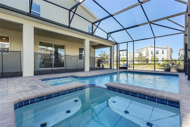 view of pool featuring an in ground hot tub, a patio area, and glass enclosure