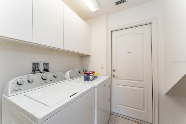 washroom featuring light tile patterned floors, washer and dryer, and cabinets