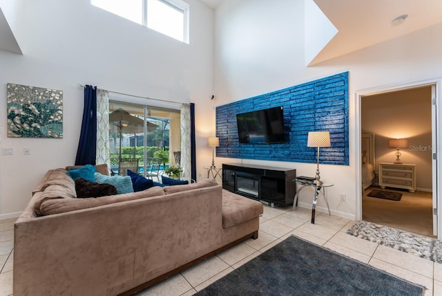 tiled living room with a healthy amount of sunlight, a fireplace, and a towering ceiling