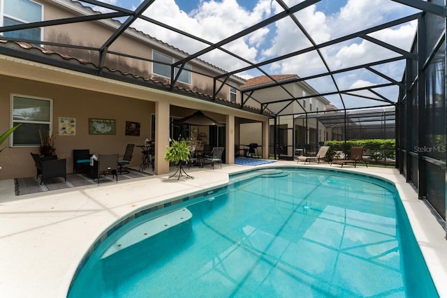 view of swimming pool with glass enclosure and a patio