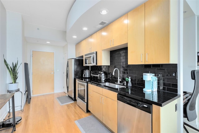 kitchen with light brown cabinetry, sink, tasteful backsplash, appliances with stainless steel finishes, and light hardwood / wood-style floors