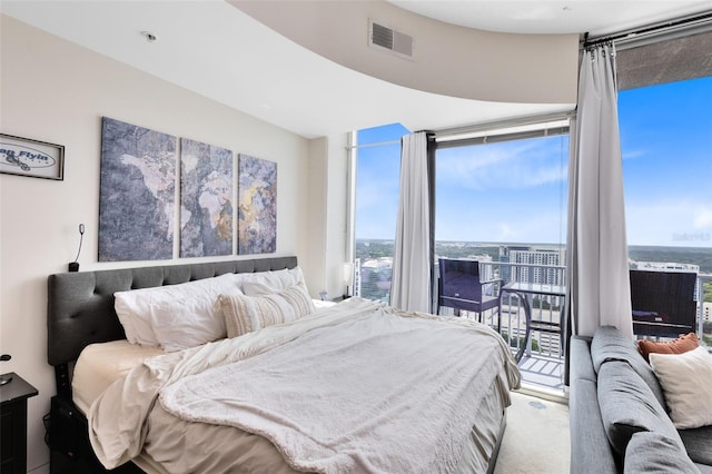 bedroom with expansive windows, carpet floors, and access to outside