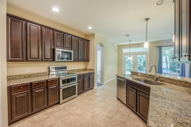 kitchen featuring appliances with stainless steel finishes, dark brown cabinets, decorative light fixtures, and sink