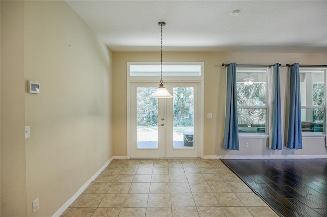 entryway with a textured ceiling, light tile patterned floors, and french doors