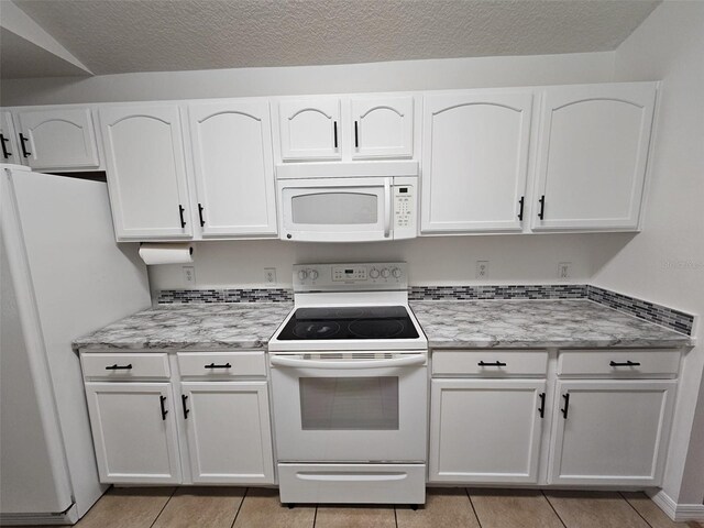 kitchen featuring white cabinetry, light tile patterned flooring, and white appliances