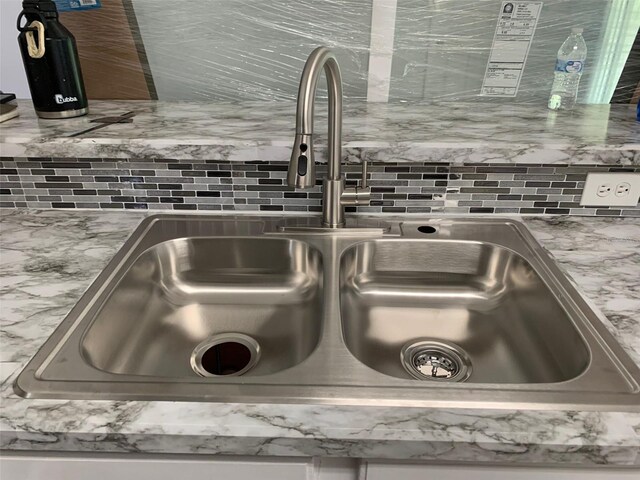 room details featuring sink, backsplash, and light stone counters