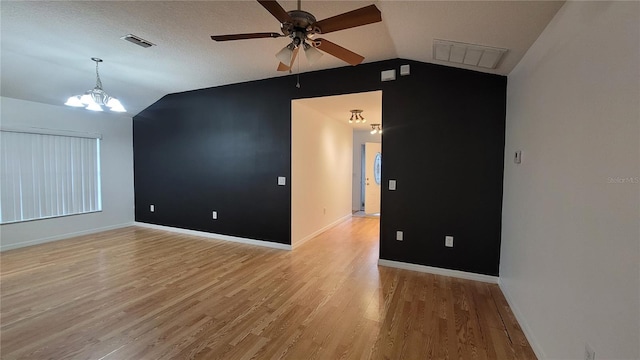 empty room with light wood-type flooring, vaulted ceiling, and ceiling fan with notable chandelier