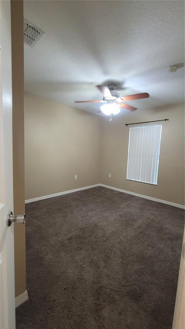 carpeted spare room featuring ceiling fan and a textured ceiling