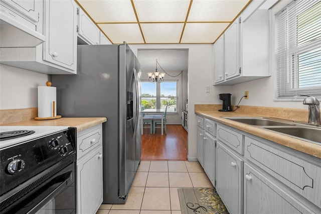 kitchen with sink, an inviting chandelier, black electric range oven, white cabinetry, and light tile patterned floors