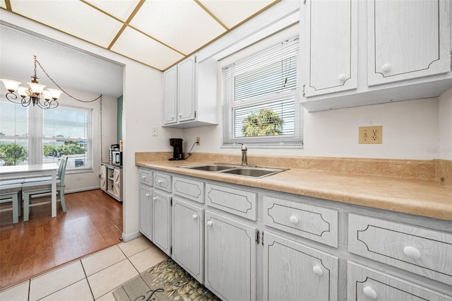 kitchen featuring light tile patterned floors, sink, white cabinets, and plenty of natural light