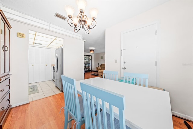 dining room with light wood-type flooring and a notable chandelier