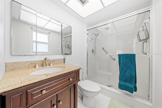 bathroom featuring toilet, a shower with door, tile patterned floors, and vanity