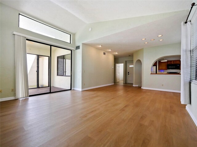 unfurnished living room featuring vaulted ceiling and light hardwood / wood-style floors