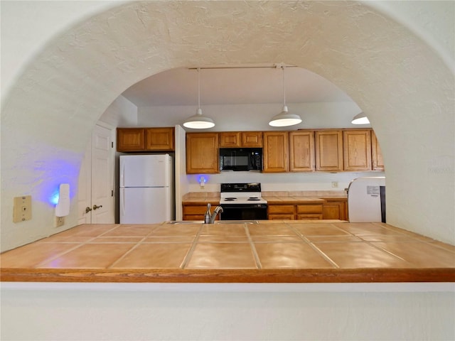 kitchen featuring pendant lighting, kitchen peninsula, and white appliances