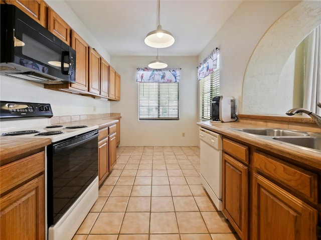 kitchen featuring hanging light fixtures, sink, light tile patterned flooring, and white appliances