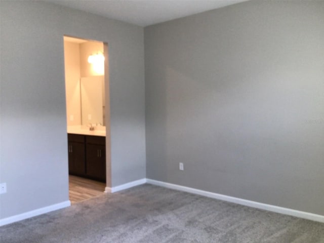 unfurnished bedroom featuring ensuite bath and light colored carpet