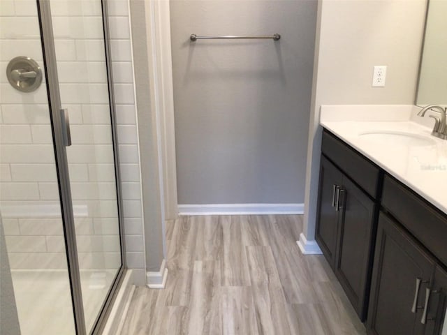 bathroom with walk in shower, wood-type flooring, and vanity