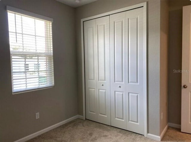 unfurnished bedroom with light colored carpet and a closet