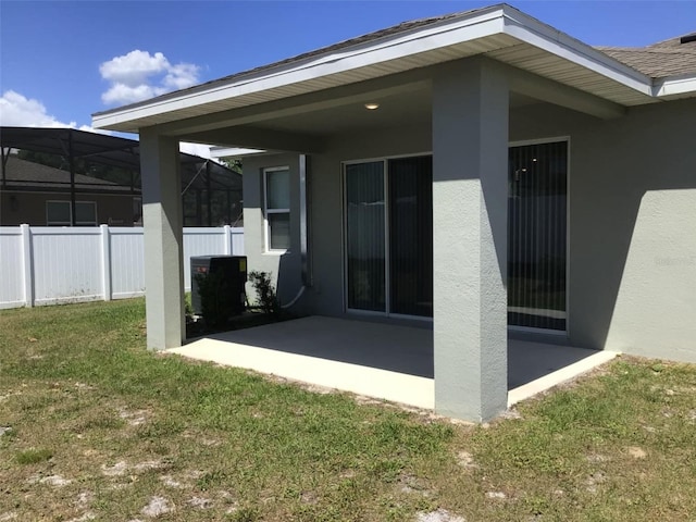 back of property with a patio, glass enclosure, and a lawn