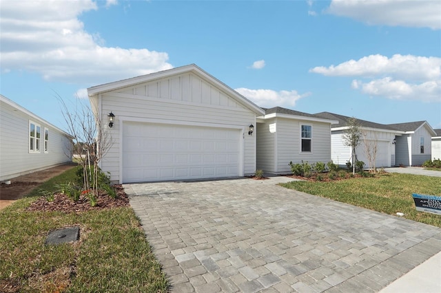 ranch-style house with decorative driveway, board and batten siding, an attached garage, and a front yard