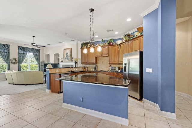 kitchen featuring sink, light tile patterned floors, stainless steel fridge, decorative light fixtures, and kitchen peninsula