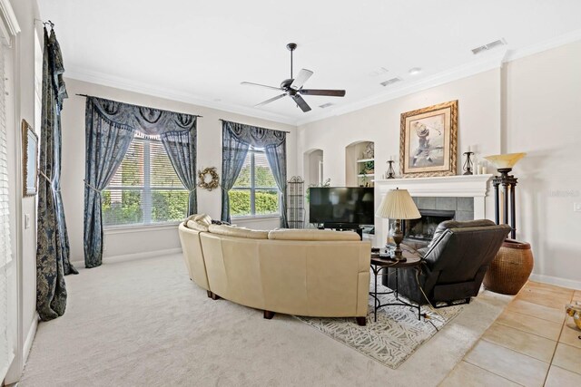 living room featuring ceiling fan, ornamental molding, a tile fireplace, and carpet