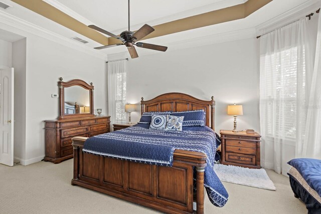 carpeted bedroom featuring a raised ceiling, ceiling fan, and ornamental molding