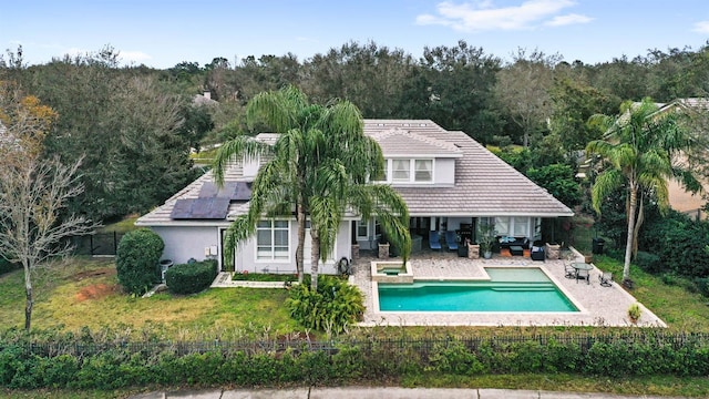 rear view of property with a fenced in pool, a patio, a yard, and solar panels