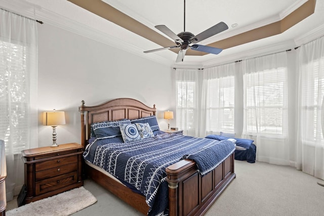 carpeted bedroom featuring ceiling fan, ornamental molding, and a tray ceiling