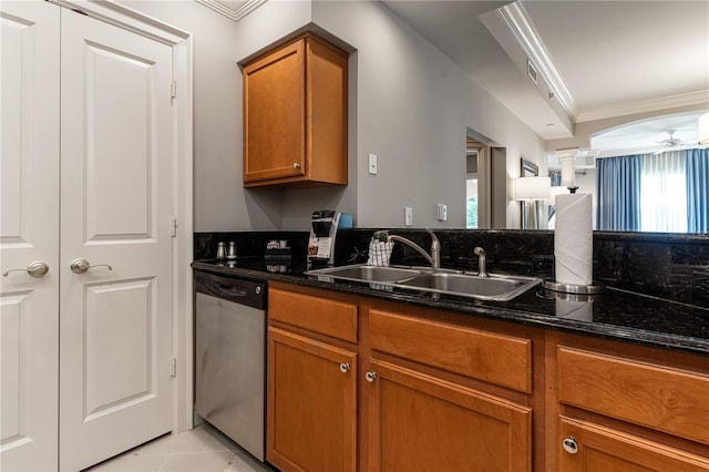 kitchen with sink, ornamental molding, dark stone counters, and dishwasher