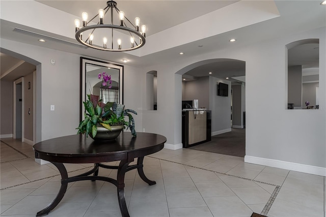 hall with light tile patterned floors and a tray ceiling